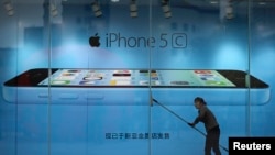 Worker cleans glass in front of an iPhone 5C advertisement at an apple store in Kunming, Yunnan province, China, Oct. 27, 2013.