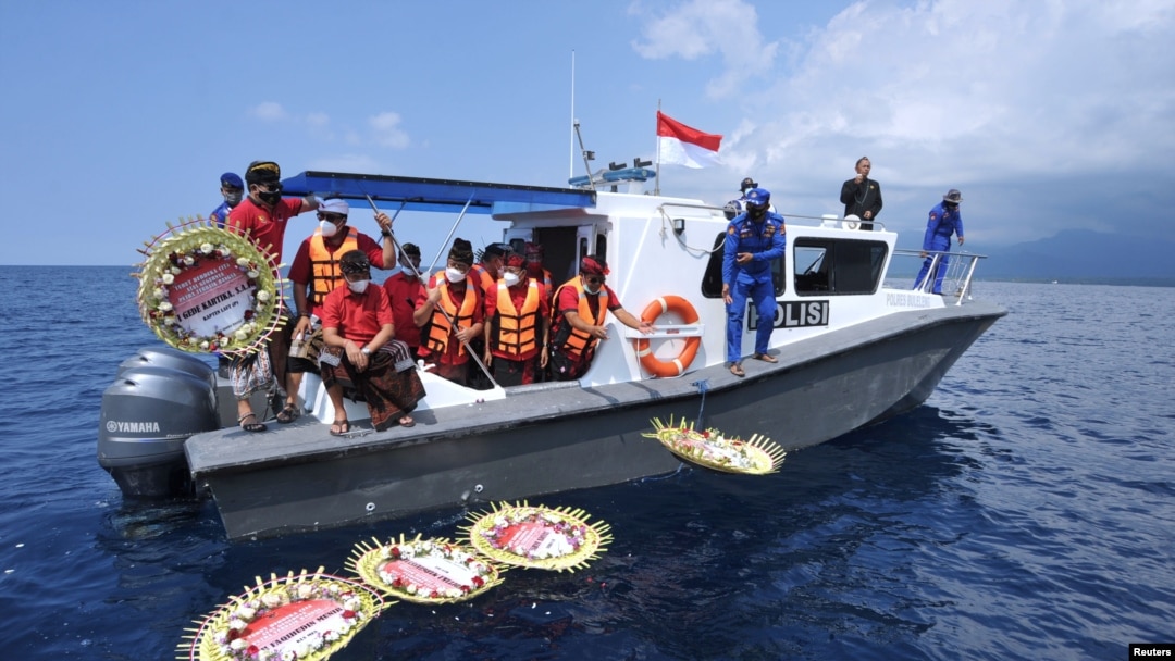 Warga melempar bunga dan kelopak bunga dengan nama awak kapal selam KRI Nanggala-402 yang tenggelam di laut, di dekat Labuhan Lalang, Bali, 26 April 2021. (Foto: Antara/Fikri Yusuf via Reuters)