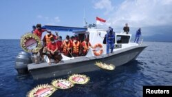 Warga melempar bunga dan kelopak bunga dengan nama awak kapal selam KRI Nanggala-402 yang tenggelam di laut, di dekat Labuhan Lalang, Bali, 26 April 2021. (Foto: Antara/Fikri Yusuf via Reuters)