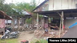 Seorang warga di depan rumah yang kehilangan bagian dinding yang roboh dalam gempa bumi magnitudo 6,2 di Majene, Sulawesi Barat. Jumat, 29 Januari 2021. (Foto: VOA/Yoanes Litha)