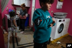 Rukiye Sahin, 28, talks to her daughter Dilan, 5, near her son Atakan, 11, in the family's one-room apartment in the Tarlabasi neighborhood in Istanbul, Turkey, Dec. 4, 2024.