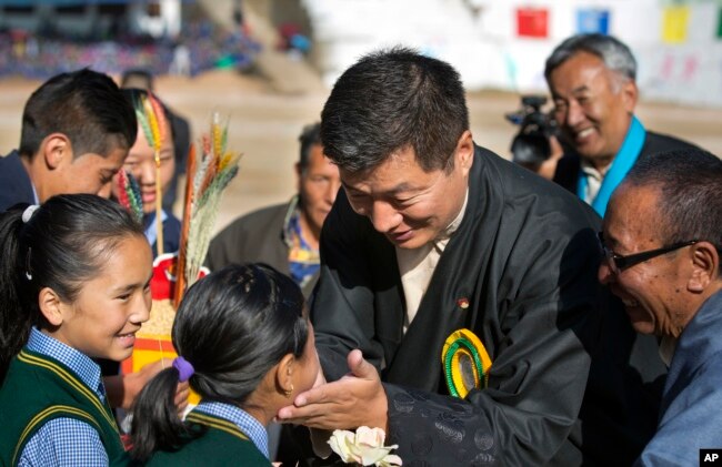 FILE - President of the Tibetan administration in exile Lobsang Sangay, center, greets a child as he arrives to attend the founding anniversary celebrations at the Tibetan Children's Village School in Dharmsala, India, Oct. 23, 2017.