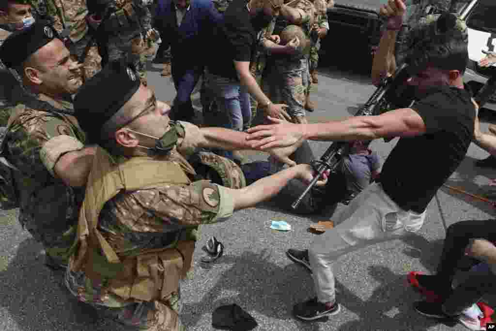 An opponent of Judge Ghada Aoun grabs the weapon of a soldier, after he was hit, during a sit-in outside the Justice Palace in Beirut, Lebanon.
