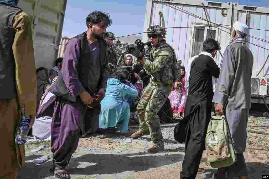 A U.S. soldier points his gun towards an Afghan passenger at the Kabul airport in Kabul as thousands of people mobbed the city&#39;s airport trying to flee the Taliban&#39;s hardline brand of Islamist rule.