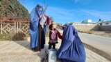 تیم واکسیناتوران در حال انداختن قطره خوراکی پولیو به دهان کودکی در افغانستان