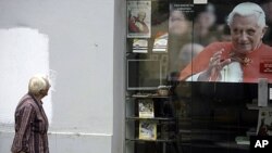 A woman passes by a poster depicting Pope Benedict XVI in Zagreb, Croatia, June 3, 2011