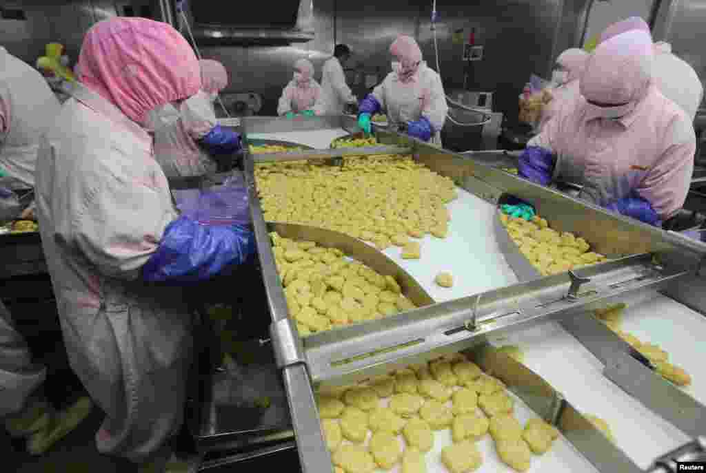 Employees work at a production line at the Husi Food factory in Shanghai, China, July 20, 2014. The Shanghai Food and Drug Administration closed Shanghai Husi Food Co Ltd, a local unit of OSI, and seized meat products suspected of being beyond their expiration date, according to a statement from the Shanghai Municipal Food and Drug Administration.