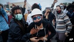 A protester reacts after being hit by crowd dispersal rounds as a group of demonstrators are detained prior to arrest at a gas station on South Washington Street, Sunday, May 31, 2020, in Minneapolis. (AP Photo/John Minchillo)