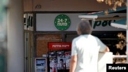 A man stands nearby as a "24/7" open sign is seen at the entrance of a food store in Tel Aviv, Israel, Sept. 20, 2016.