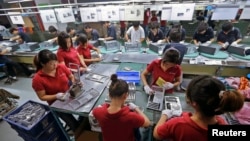 FILE - Employees work at a Foxconn factory in Wuhan, Hubei province, China.