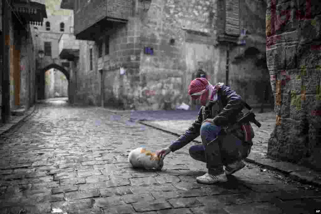 Un combattant de l&#39;Arm&eacute;e syrienne libre donnant &agrave; manger &agrave; un chat dans la vieille ville d&#39;Alep. 