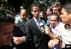 FILE - Opposition National Assembly President Juan Guaido talks with reporters upon his arrival to the Venezuelan Central University for a conference on economic plans for reviving the country in Caracas, Venezuela, Jan. 31, 2019.
