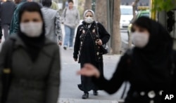 FILE - Iranian women wear masks to help guard against dangerous levels of air pollution as they walks in the center of the smog-filled capital, Tehran, Iran.