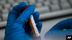 FILE - An employee of the Russia's national drug-testing laboratory holds a vial in Moscow, Russia. On Monday, July 18, 2016 WADA investigator Richard McLaren confirmed claims of state-run doping in Russia. 