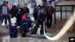 Palestinian rescue members help residents evacuate from a flooded area following heavy rains in Gaza City, Dec. 13, 2013.