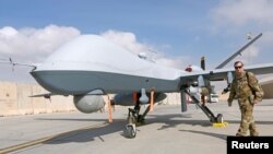 FILE - U.S. Air Force officer passes in front of a MQ-9 Reaper drone, one of a squadron that has arrived to step up the fight against the Taliban, at the Kandahar air base, Afghanistan, Jan. 23, 2018. 