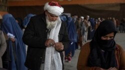 People count banknotes after receiving money from a World Food Program, in Kabul, Afghanistan on November 20, 2021. Formerly financially secure families in Afghanistan are having to depend on money from WFP to survive. (AP Photo/Petros Giannakouris)