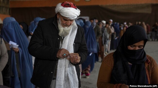 People count banknotes after receiving money from a World Food Program, in Kabul, Afghanistan on November 20, 2021. Formerly financially secure families in Afghanistan are having to depend on money from WFP to survive. (AP Photo/Petros Giannakouris)