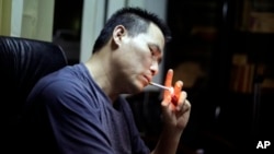 In this June 30, 2010 file photo, Prominent Chinese human rights lawyer Pu Zhiquiang lights a cigarette during an interview at his office in Beijing. 