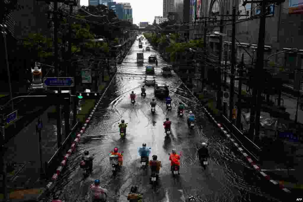 Motorists drive through a flooded street after heavy rain in Bangkok.