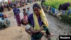 A Rohingya refugee woman who crossed the border from Myanmar carries her daughter and searches for help in Palang Khali, Bangladesh October 17, 2017.