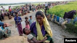 Seorang wanita pengungsi Rohingya yang melintasi perbatasan dari Myanmar sehari sebelumnya, menunggu untuk mendapat izin dari tentara Bangladesh untuk melanjutkan perjalanan ke kamp-kamp pengungsian, di Palang Khali, Bangladesh, 17 Oktober 2017.