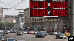 FILE - Cars drive past an exchange office sign showing the currency exchange rate in Moscow, Russia, Aug. 10, 2015.