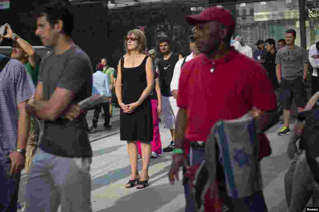 People observe a moment of silence honoring the victims of the September 11 attacks outside the World Trade Center site in New York, September 11, 2013.