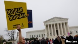 Una manifestante sostiene un cartel frente a la Corte Suprema de EE.UU. que dice no a la restricción, no al muro, mientras los jueces del máximo tribunal debaten restricción migratoria del presidente Donald Trump el miércoles, 25 de abril, de 2018.
