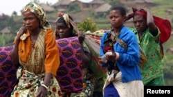 FILE - Women carry their belongings as they return to Kanyabayonga town, Democratic Republic of Congo.