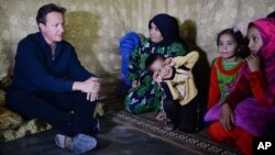 British Prime Minister David Cameron meets Syrian refugee families at a tented settlement camp in the Bekaa Valley on the Syrian - Lebanese border, Sept. 14, 2015. 