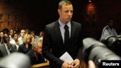 Oscar Pistorius stands in the dock during a break in court proceedings at the Pretoria Magistrates court, February 20, 2013.