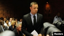 Oscar Pistorius stands in the dock during a break in court proceedings at the Pretoria Magistrates court, February 20, 2013. 