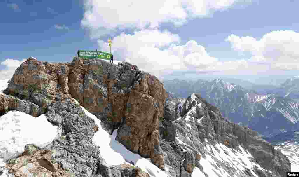 A banner reading 'The water will soon rise this high!' is rolled out by activists of German environmental Greens party at Germany's highest mountain, the 2,962 meter (9,718 feet) Zugspitze in Grainau near Garmisch-Partenkirchen, southern Germany ahead of the G7 summit in Elmau.