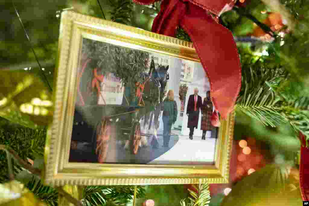 A photo of former President Donald Trump and first lady Melania Trump sits in a Christmas tree in the State Dining Room of the White House during a press event for the White House holiday decorations, Monday, Nov. 29, 2021, in Washington. (AP Photo/Evan Vucci)