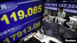 Para pegawai perusahaan perdagangan valuta asing memantau tingkat pertukaran mata uang di Tokyo (26/8). (Reuters/Yuya Shino)