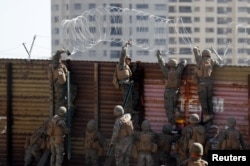U.S. Marines install concertina wire along the top of the primary border wall at the port of entry next to Tijuana in San Ysidro, San Diego, California, Nov. 9, 2018.