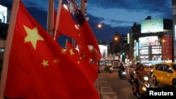 FILE - Flags of China and Taiwan flutter next to each other during a rally calling for peaceful reunification, days before the inauguration ceremony of President Tsai Ing-wen, in Taipei, Taiwan, May 14, 2016.
