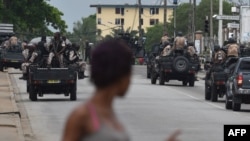 Une passe se retourne pour regarder des véhicules des forces de sécurité en patrouille à Abidjan, Cote d’Ivoire, 12 mai 2017. 