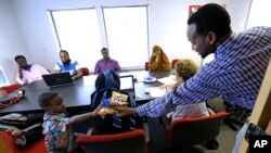 FILE - Somali immigrant leader Jamal Dar, right, who arrived in the U.S. two decades ago from Kenya, hands out snacks to a boy at a community engagement and civic language class for former Somali residents in East Portland, Oregon, July 21, 2015.