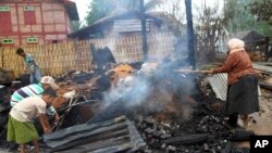 A woman and children clear debris of a burnt-down building in Htan Gone village of Kantbalu township, Sagaing Division, Burma, Aug. 26, 2013. 