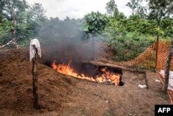 Health workers burn mattresses used by patients with Ebola virus, on Aug. 21, 2018 in Mangina, near Beni, in the North Kivu province of the DRC.