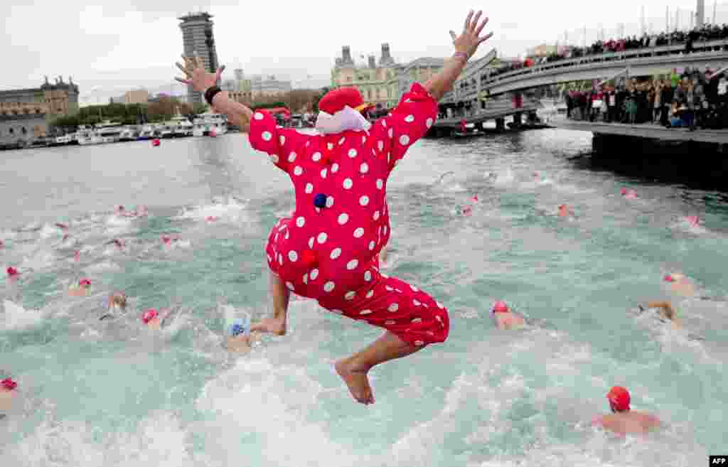 Seorang warga dengan pakaian menyolok terjun ke laut untuk berpartisipasi pada acara Copa Nadal atau &#39;Piala Natal&#39; di dekat pelabuhan Barcelona, Spanyol. 