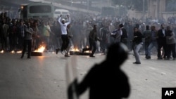 Egyptian anti-government activists throw stones at riot police during clashes in Cairo, Egypt, Jan. 26, 2011.