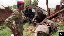 FILE—A Rwanda Patriotic Front (RPF) rebel walks by the the site of a April 6 plane crash which killed Rwanda's President Juvenal Habyarimana in this May 23, 1994 file photo in Kigali.