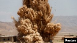 FILE - Members of the Sinjar Resistance Units (YBS), a militia affiliated with the Kurdistan Workers' Party (PKK), detonate improvised explosive devices captured from Islamic State fighters near village of Umm al-Dhiban, northern Iraq, April 30, 2016.