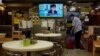 A restaurant employee cleans the floor as a TV screens show Hong Kong Chief Executive Carrie Lam's announcement that the government, invoking an emergency ordinance, will postpone legislative elections, July 31, 2020.