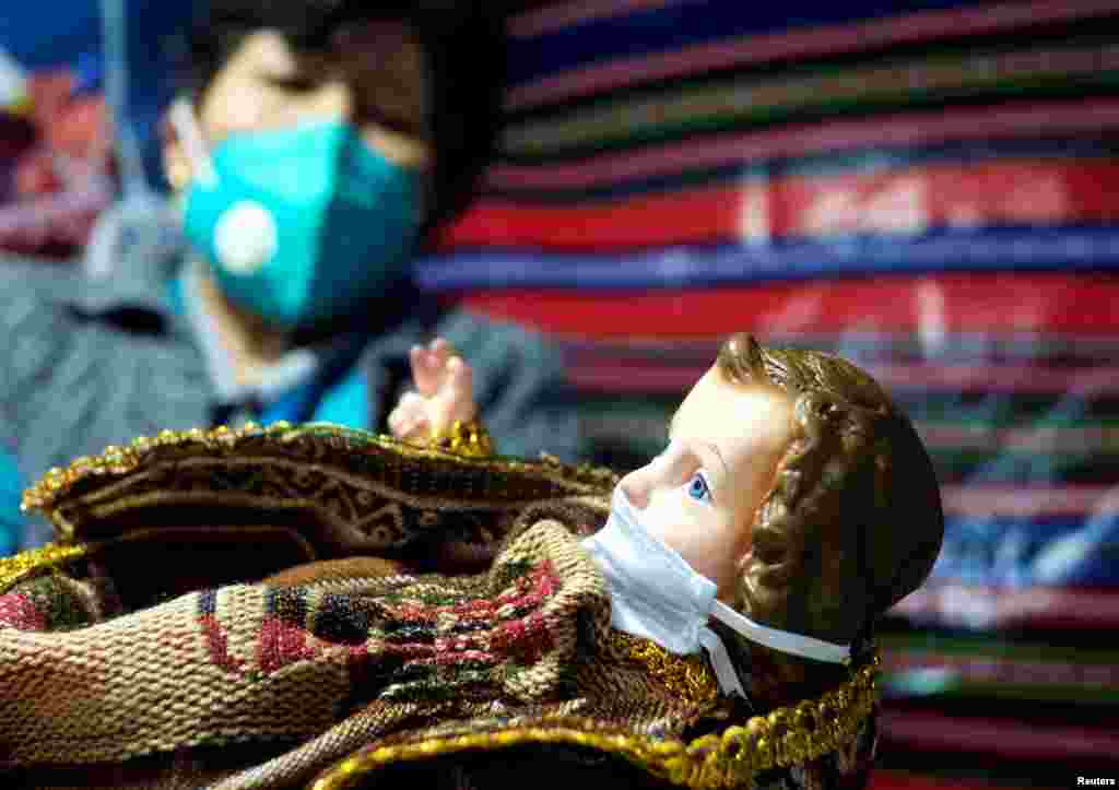 Una vendedora sostiene una imagen que representa al ni&#241;o Jes&#250;s con una m&#225;scara, antes de la celebraci&#243;n de Navidad, en la feria de Navidad en La Paz, Bolivia, 9 de diciembre de 2020. [Reuters].