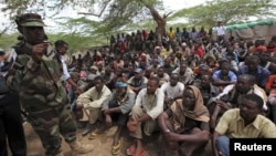 Members of al- Qaida-linked militant group al-Shabab listen to a Somalia government soldier after their surrender to the authorities in the north of Somalia's capital Mogadishu, September 24, 2012.