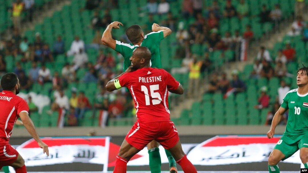 Pesepak bola Palestina Abdelatif Bahdari (tengah) berancang-ancang mengambil bola dengan seorang pesepak bola Irak dalam pertandingan persahabatan antara Irak dan Palestina di Stadion Basra Sports City, 8 Mei 2018, di Kota Basra, sebelah selatan Irak. 